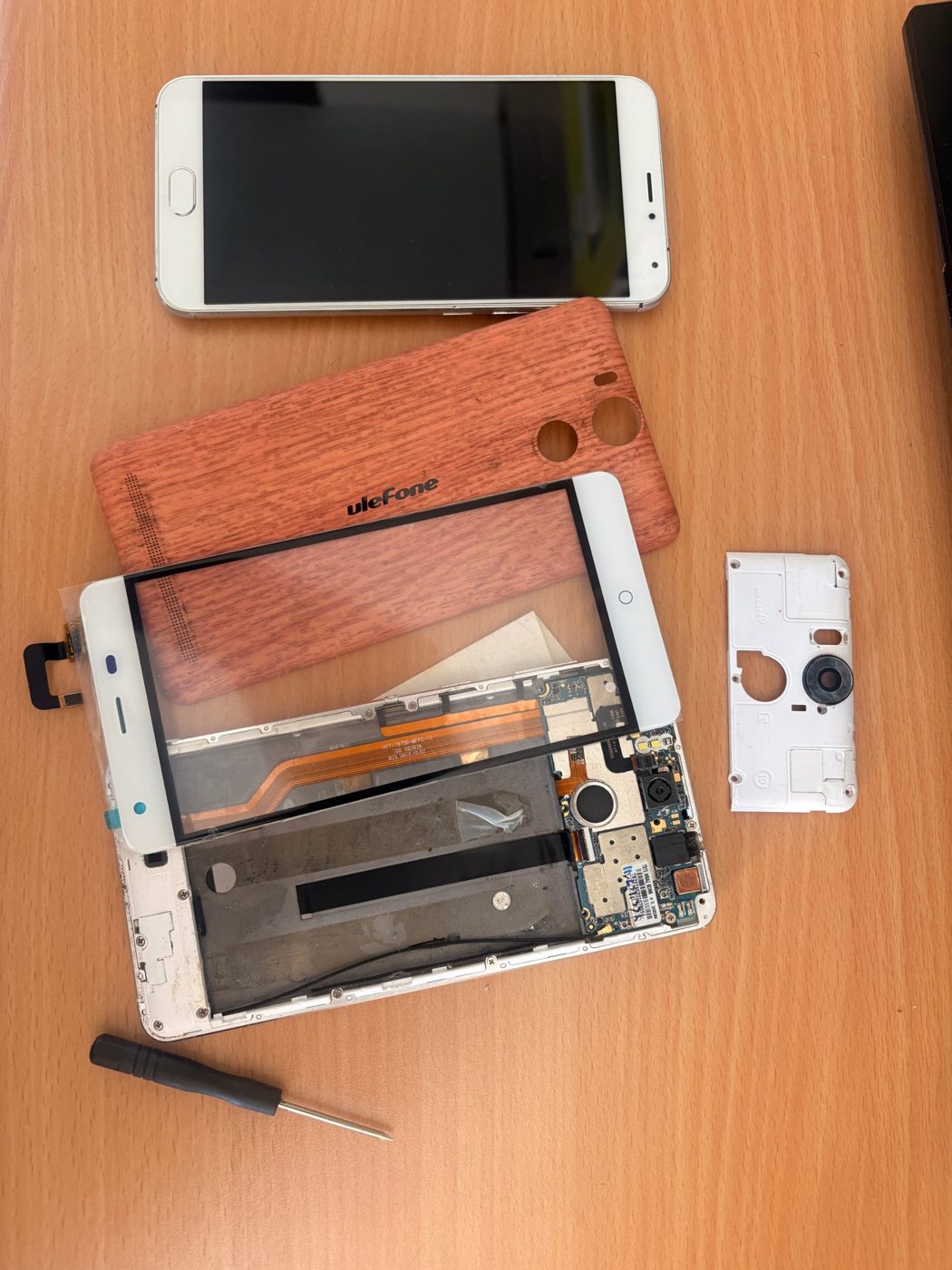 Móvil Ulefone desmontado con la pantalla nueva y el destornillador